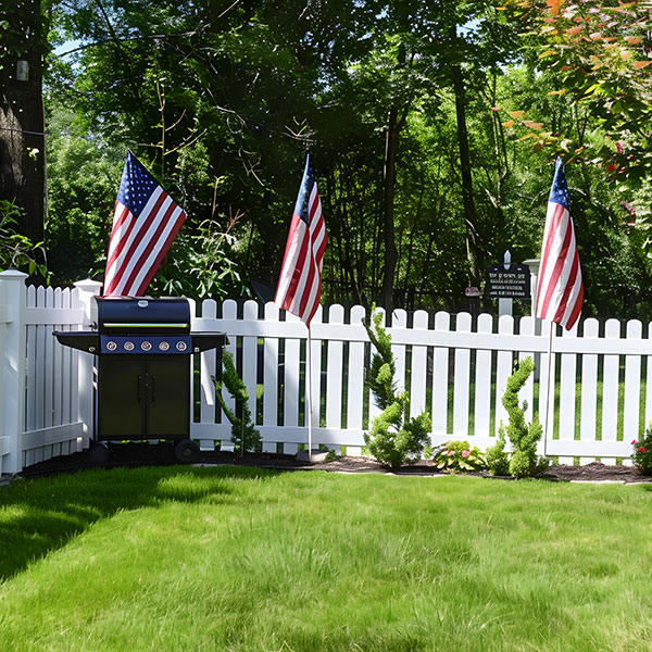 Patriotic white vinyl yard fence with plants